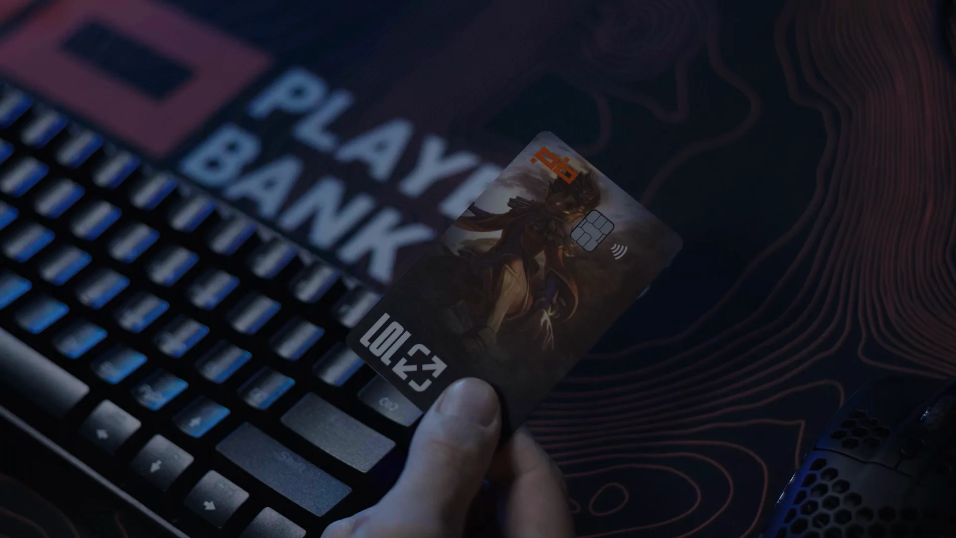Cartão do Players Bank com arte de League of Legends sobre um teclado gamer